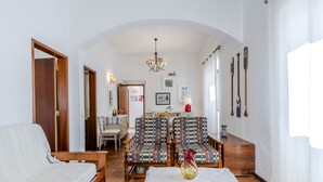 A cozy living room with a sofa, a dining table with chairs, and a chandelier. - #341 Casa da Guida | Central & Cozy (Albufeira)
