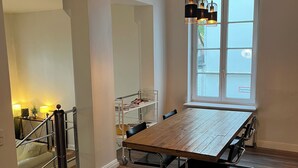 A spacious dining area with a wooden table and chairs, a metal railing, and a large window with a view. - Stylish apartment in Hamburg-Uhlenhorst (Hamburg)
