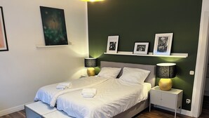 A neatly made bed with white linens and two rolled towels, a bedside table with a lamp, and a small cabinet. - Stylish apartment in Hamburg-Uhlenhorst (Hamburg)