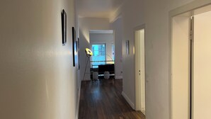 A hallway with wooden flooring, white walls, and a door on the right. - Stylish apartment in Hamburg-Uhlenhorst (Hamburg)