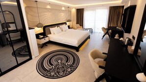 A modern hotel room with a large bed, a desk, a chair, a TV, and a dining area. - PORTO DE GALATA LA BOHEMIAN HOTEL (Istanbul)