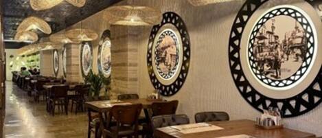 A restaurant with long tables, hanging wicker lamps, and circular wall decorations.