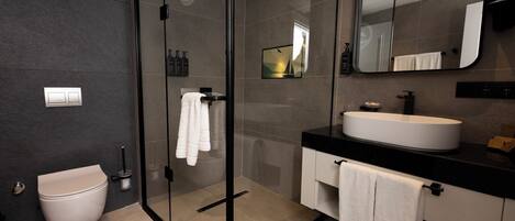 A modern bathroom with a glass-enclosed shower, a white sink, and a large mirror.
