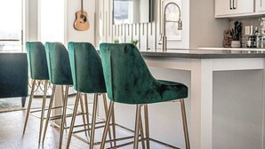 A modern kitchen with a bar area featuring green velvet bar stools with gold legs. - Harmony House #6–Roomy Retreat–Sleeps 12 (Nashville)