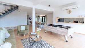 A modern living room with a pool table, a staircase, and a dining area. - Minimalist 4BR Private Cozy Pool Villa - VVP26.11 (Pattaya)