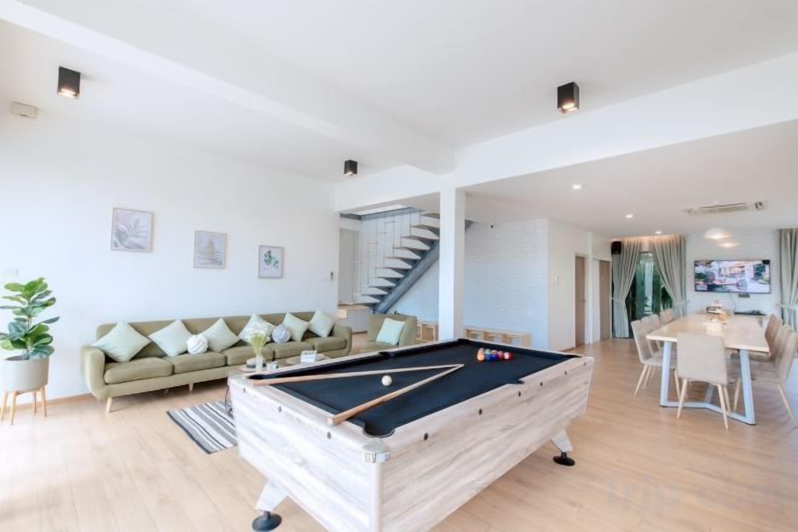 A modern living room with a pool table, a sofa, and a dining area.