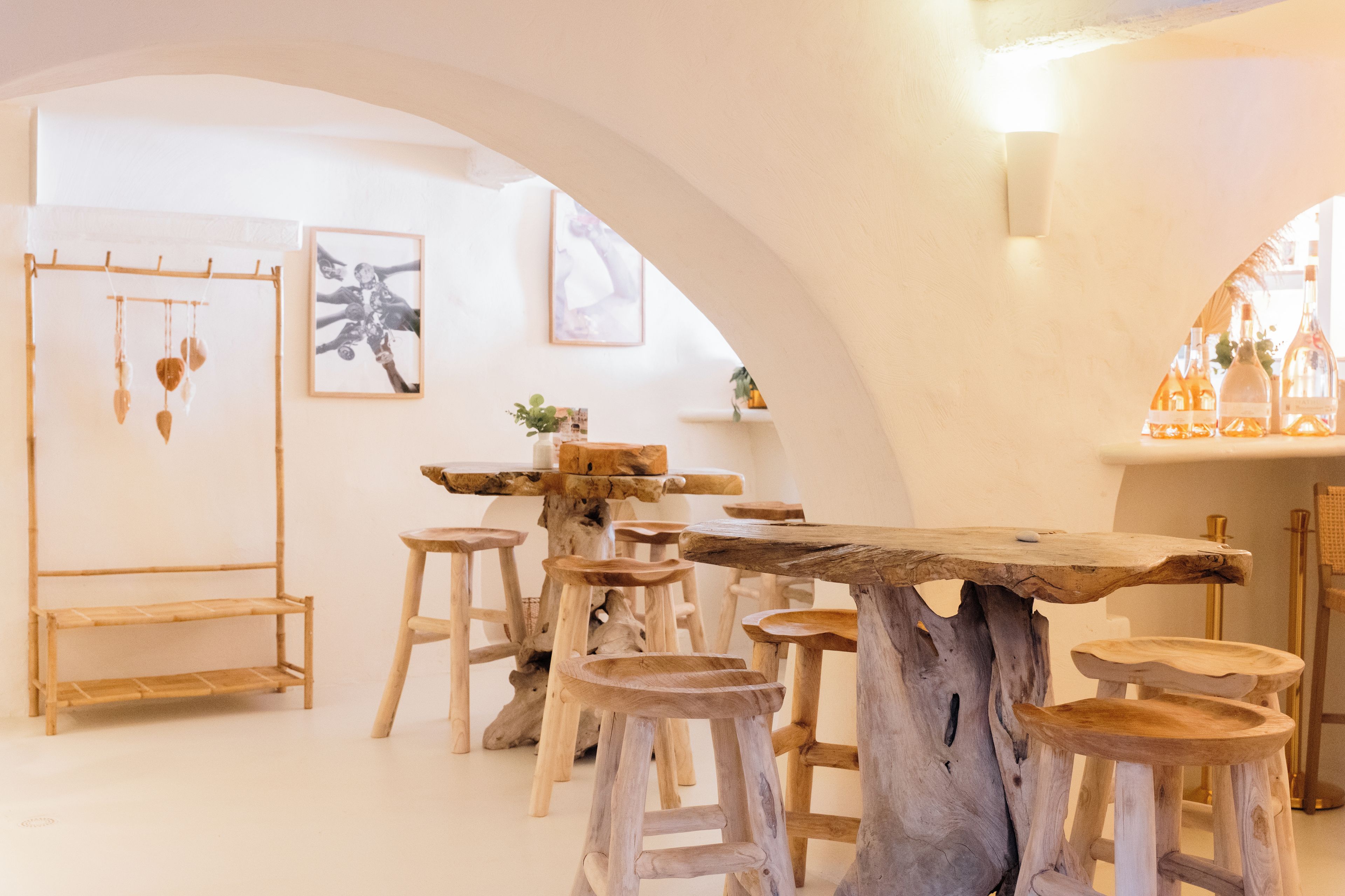 Un interior rústico con una mesa y taburetes de madera, obras de arte enmarcadas en las paredes y un adorno colgante.