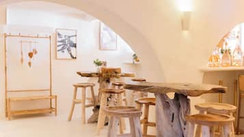 Un interior rústico con una mesa y taburetes de madera, obras de arte enmarcadas en las paredes y un adorno colgante.