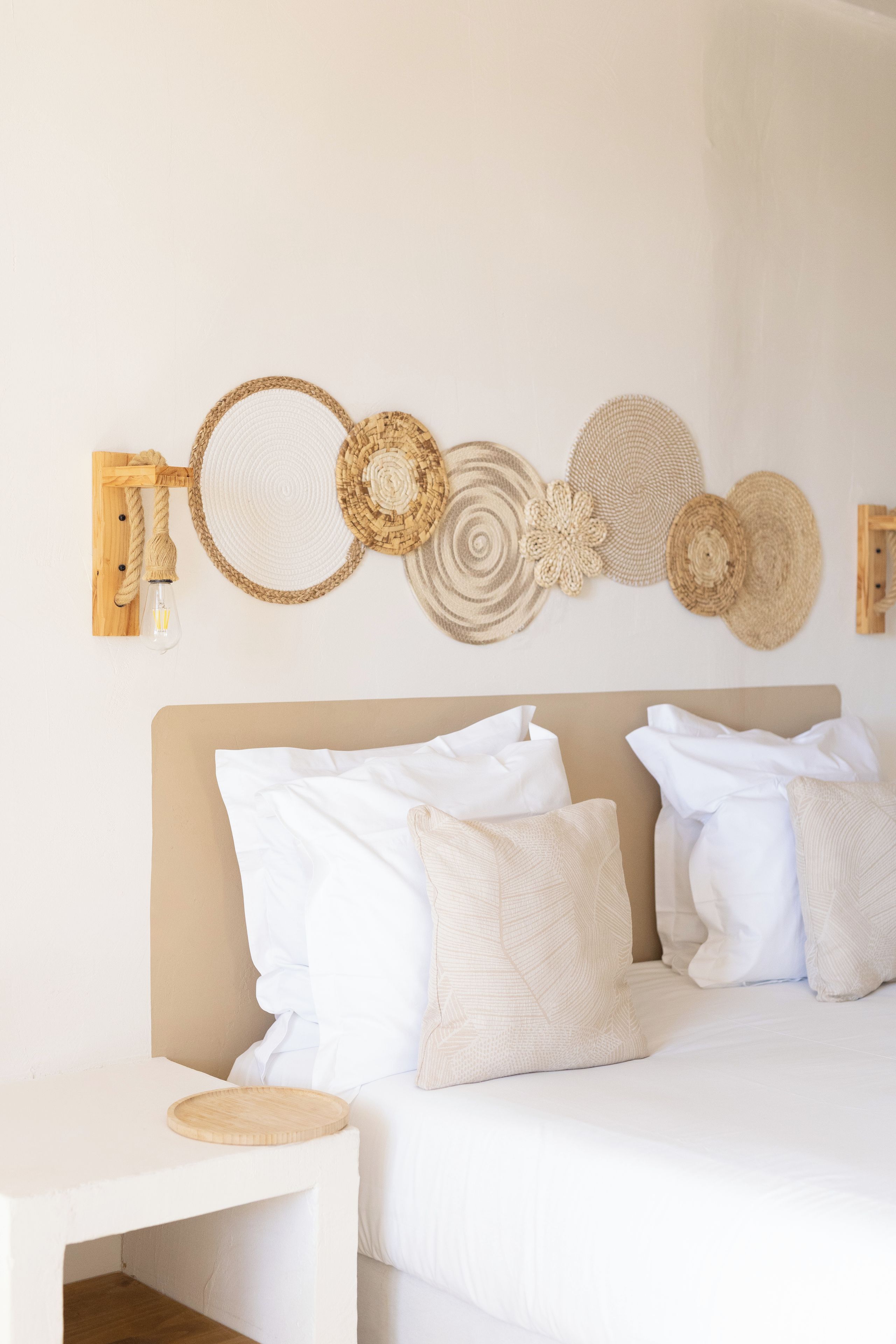 A bedroom with a bed, pillows, a bedside table, and a wall-mounted light fixture.