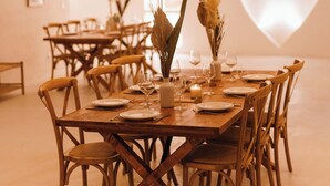 A dining area with wooden tables and chairs, hanging lights, and a large heart-shaped projection on the wall. - Auberge Tao (Biot)