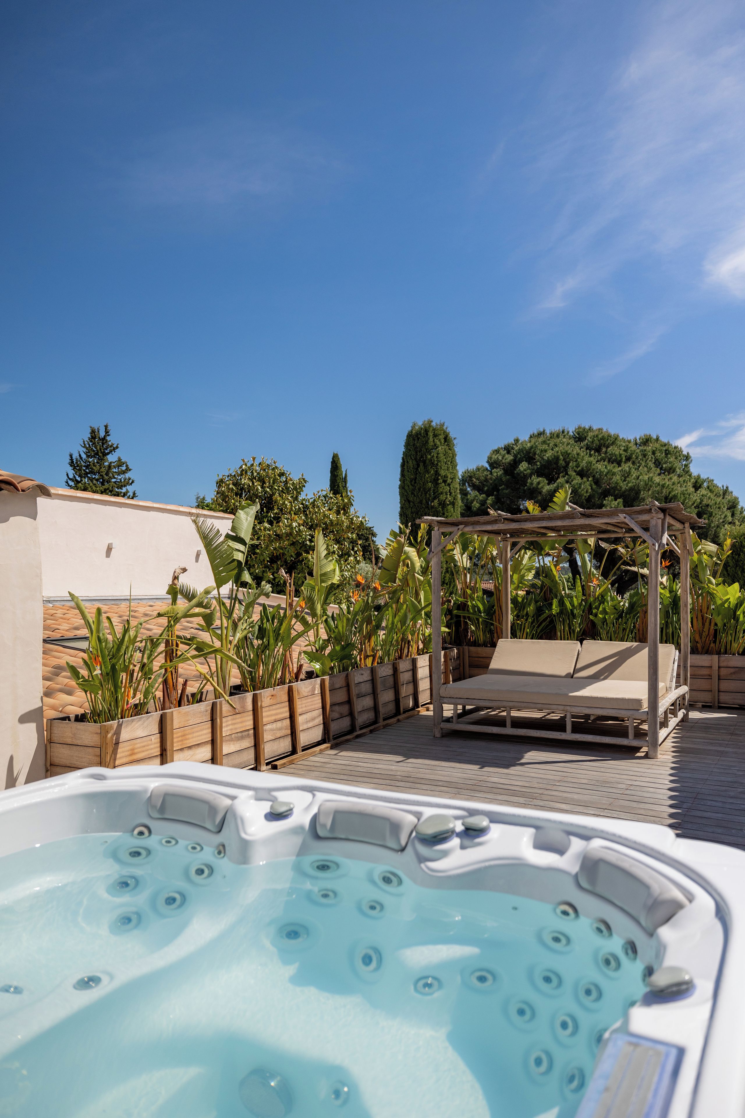 Un bain à remous avec une terrasse en bois et une pergola en bois dotée d’un banc.