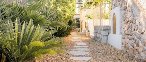 A pathway with stepping stones leading to a stone wall with a gate.