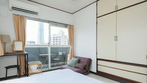 A hotel room with a bed, a desk with a lamp, a chair, a sofa, and a wardrobe. - Grace Mukojima Room 701 (Tokyo)