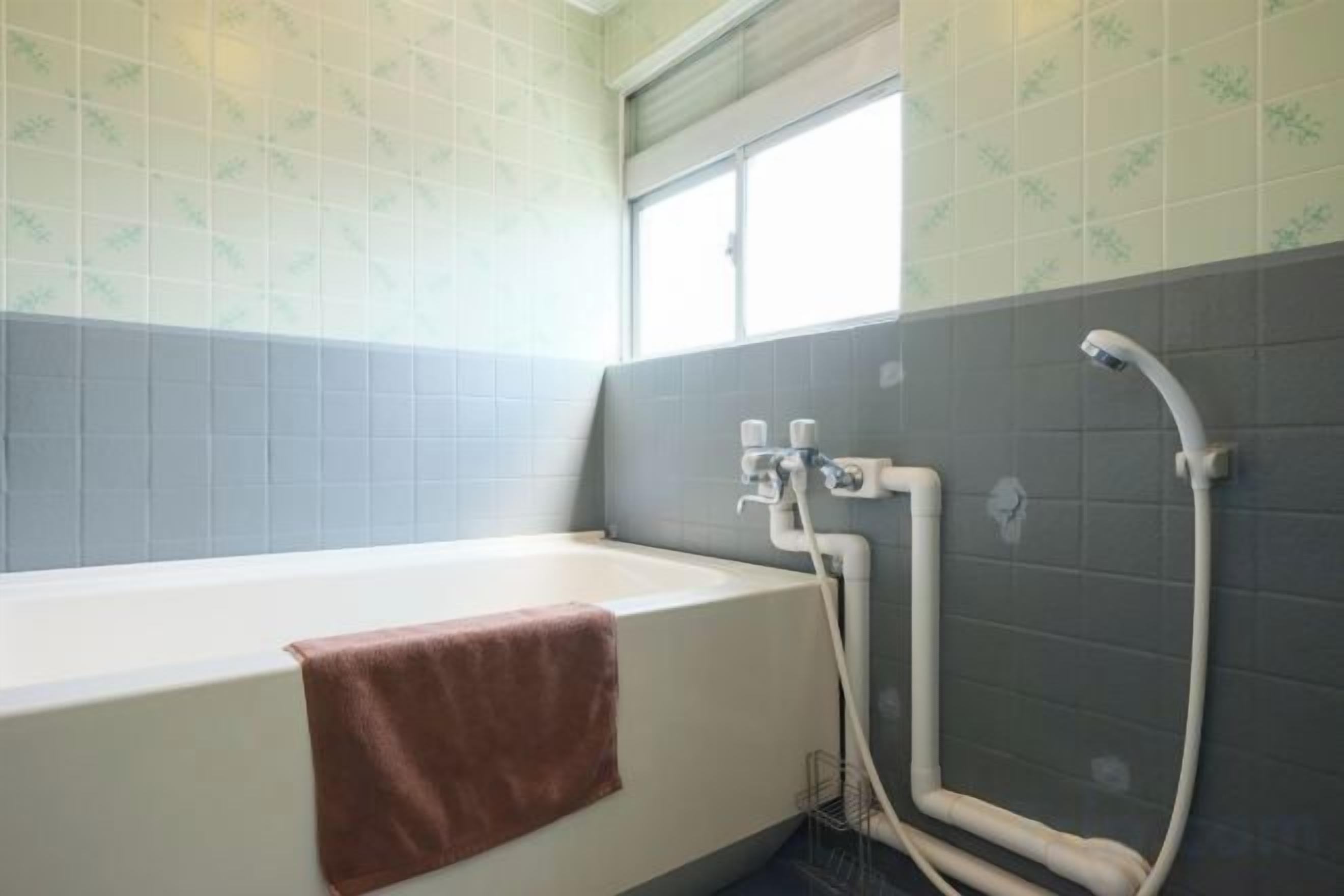 A bathroom with a bathtub, a towel, and a shower area.