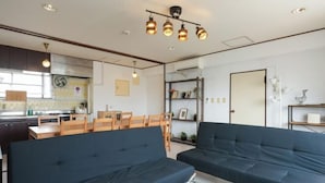 A modern living room with dark blue sofas, a wooden coffee table, and pendant lighting. - Grace Mukojima Room 701 (Tokyo)