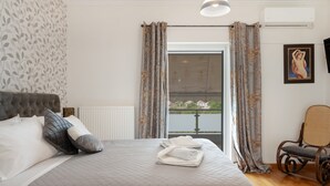 Een slaapkamer met een bed, kussens, een stoel en uitzicht door een raam.
