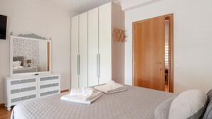 Een slaapkamer met een bed, een kapstok, een kledingkast en een houten deur.