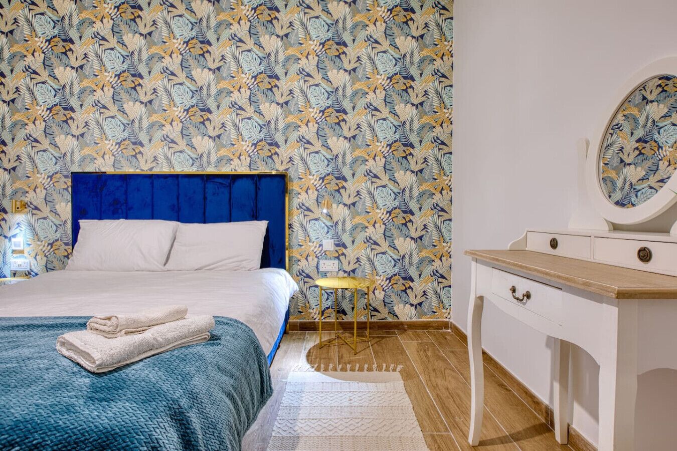 Una camera da letto con un letto, un comodino, uno specchio e carta da parati decorata.