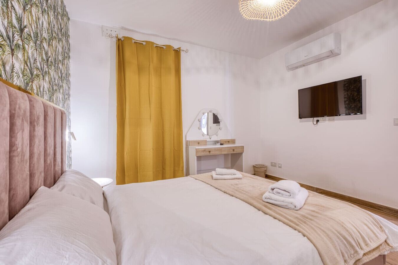 Een hotelkamer met een bed, een kaptafel met spiegel en een televisie aan de muur.