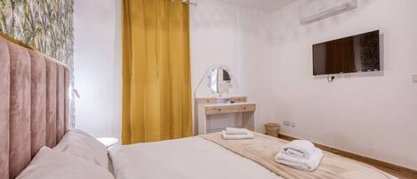 Een hotelkamer met een bed, een kaptafel met spiegel en een televisie aan de muur.