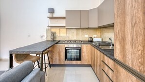 A modern kitchen with a central island, wooden cabinets, and a built-in oven. - Relaxing Xaghra Apartment With BBQ Amenities (Xaghra)