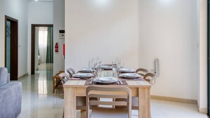 A dining area with a wooden table set for six, surrounded by chairs. - Relaxing Xaghra Apartment With BBQ Amenities (Xaghra)
