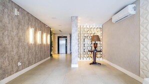 Un corridoio dal design moderno, con una parete decorata da un motivo e un pannello divisorio, illuminato da una lampada da terra.