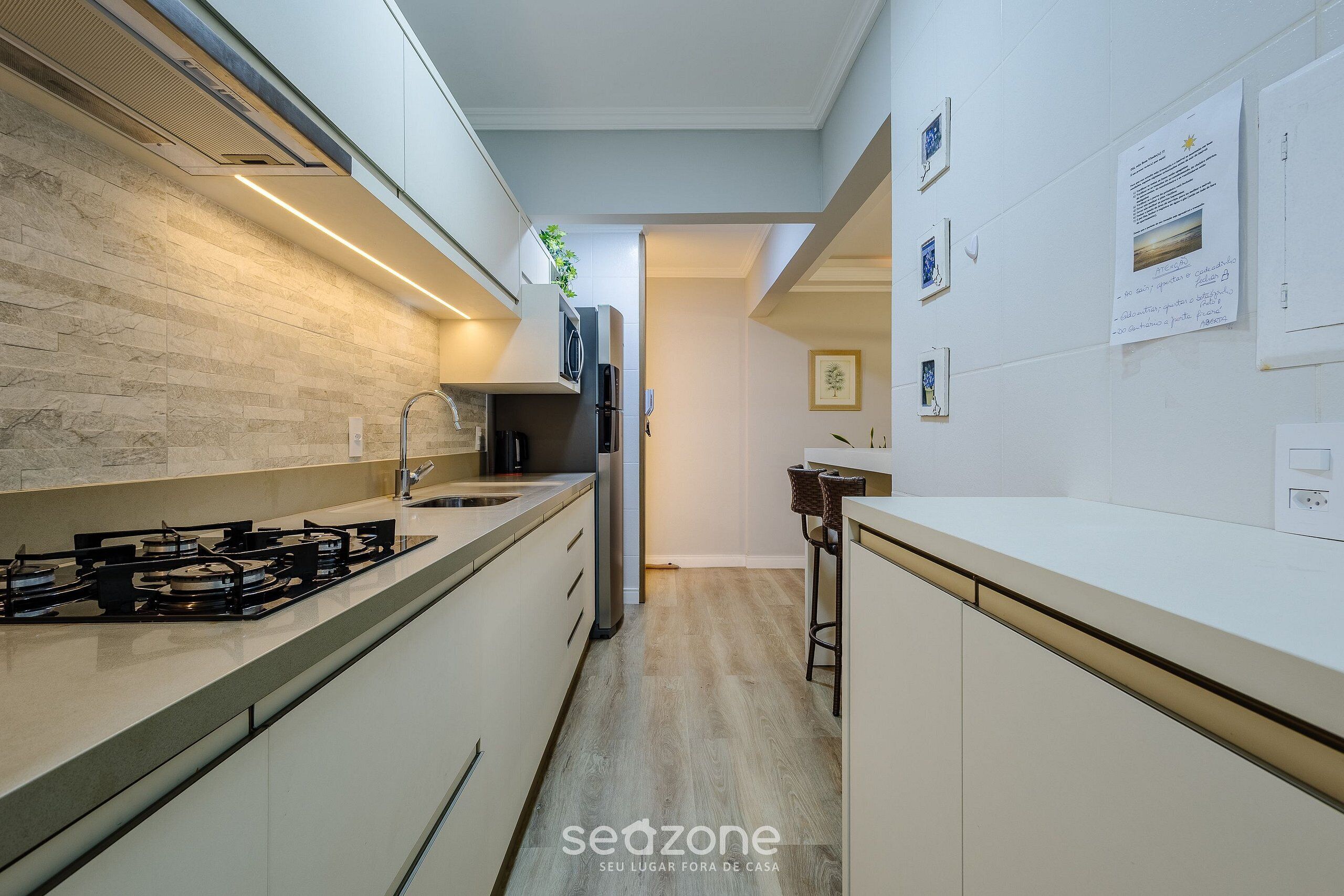 A modern kitchen with white cabinets, a gas stove, and a stainless steel refrigerator.