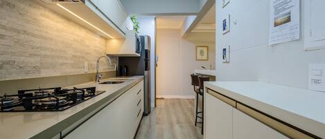 A modern kitchen with white cabinets, a gas stove, and a stainless steel refrigerator.