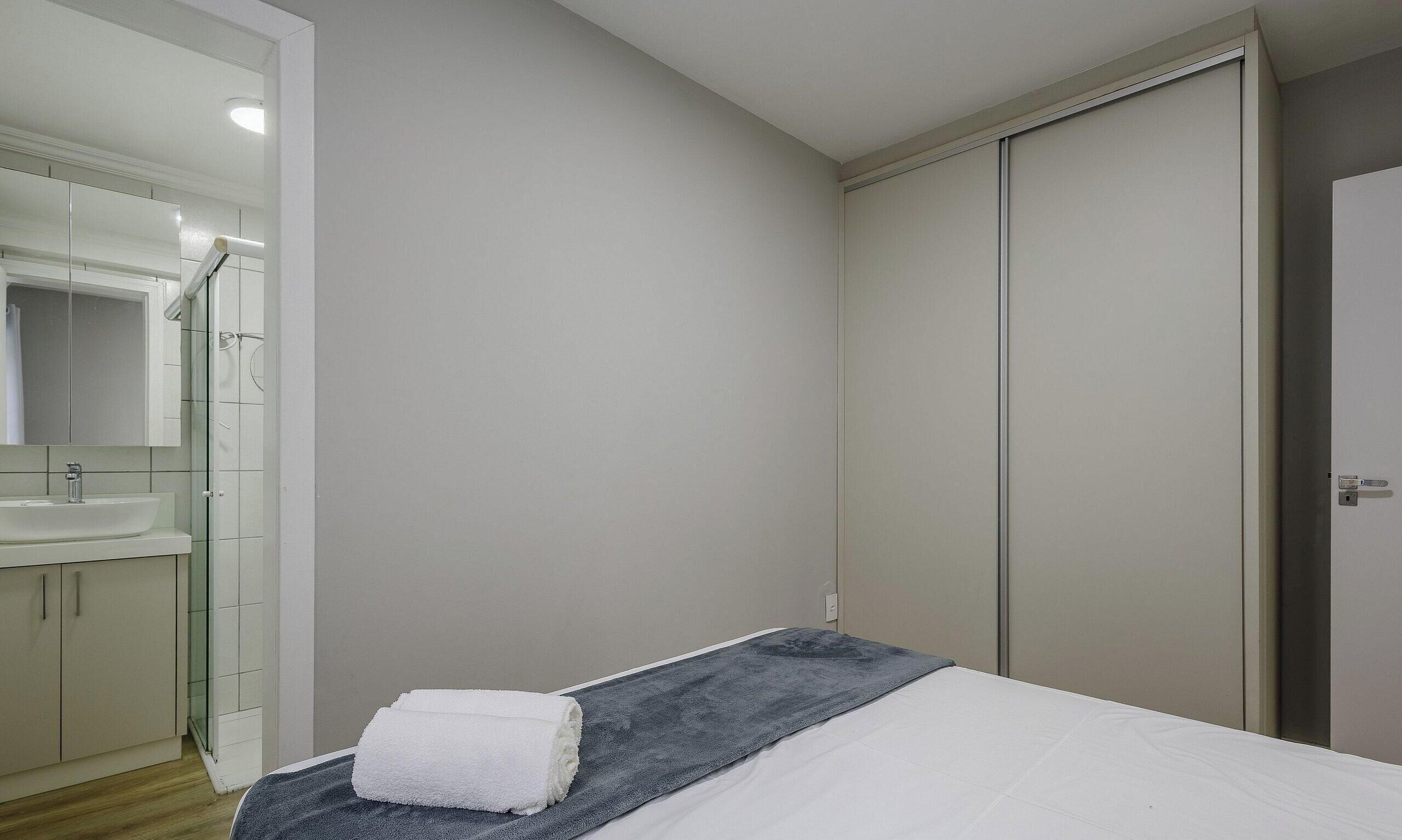 Um quarto com uma cama, um banheiro com pia e um guarda-roupa.