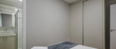 Um quarto com uma cama, um banheiro com pia e um guarda-roupa.