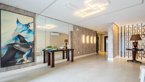 Una hall d'albergo moderna con un grande dipinto astratto, una reception e un pannello decorativo con motivi geometrici.