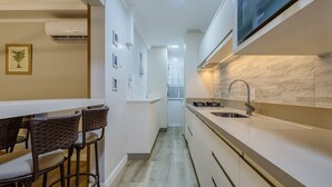Una cucina moderna con piano cottura integrato, un lavandino grande e una zona pranzo con sedie in vimini.