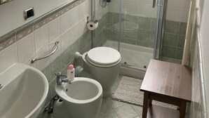 Een badkamer met douche, toilet, bidet en wastafel.