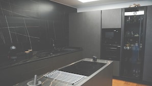 A modern kitchen with a central island, black cabinetry, and a built-in microwave.