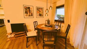 Un espace repas comprenant une table ronde, des chaises en bois, une cheminée et des œuvres d’art accrochées au mur.