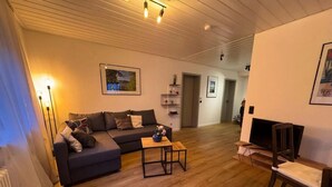Un salon avec un canapé, une table basse, un téléviseur et un fauteuil.