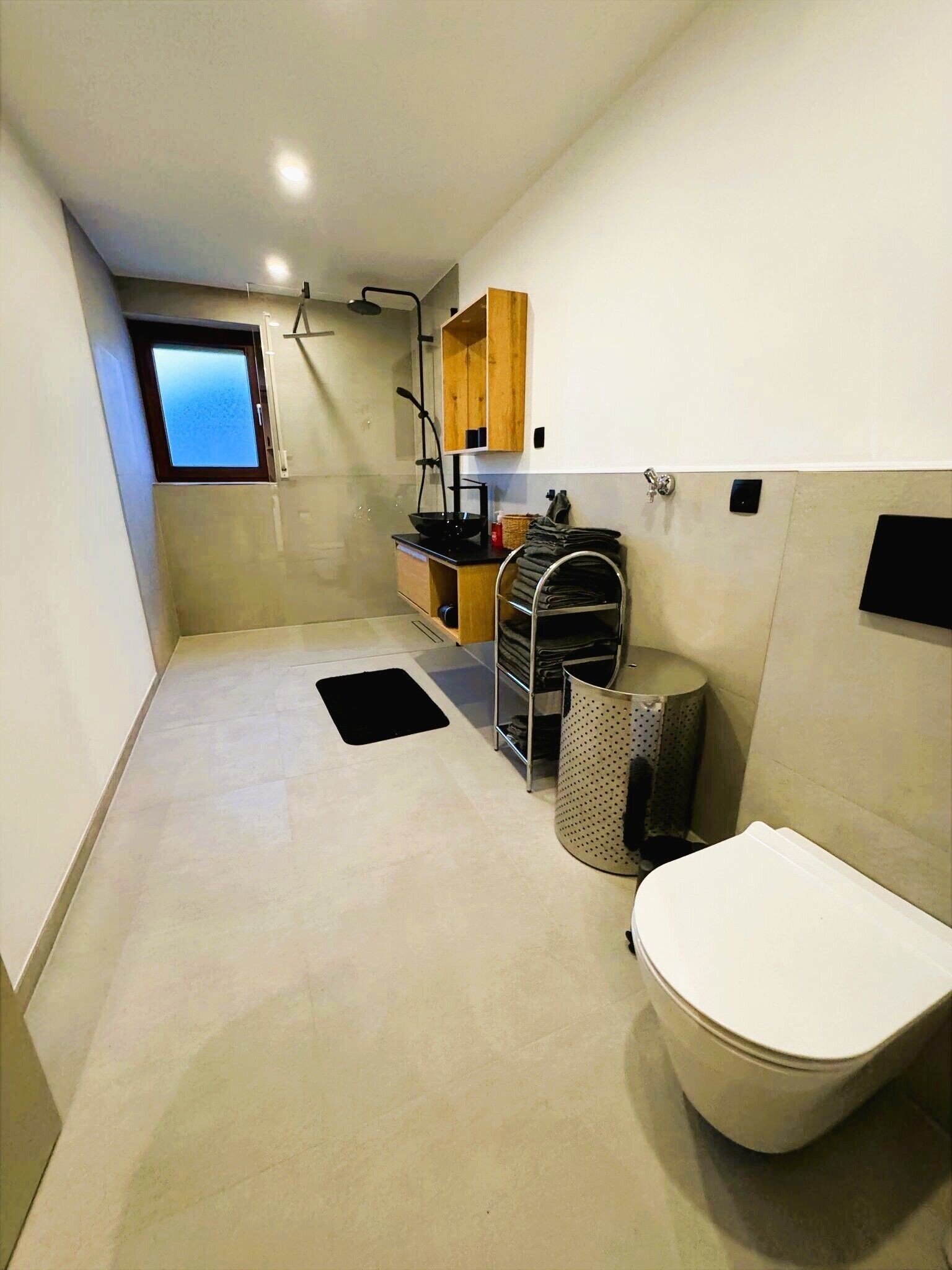 A compact bathroom with a toilet, a sink, a small window, and a towel rack.