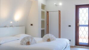 A hotel room with a bed, a wooden swing door, and a small window with a decorative pattern. - Rental in Rome San Pancrazio Penthouse (Rome)