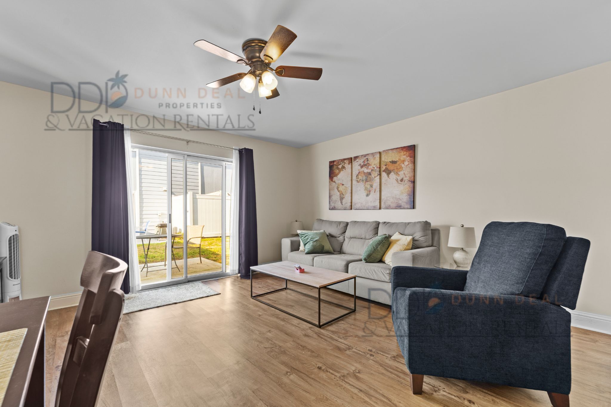 A modern living room with a sofa, armchair, coffee table, and a ceiling fan.
