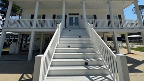 A two-story building with a central staircase leading to a balcony. - Beautiful Waterfront House with Pool sleeps 11 (Pass Christian)