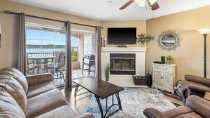 A living room with a fireplace, a television, and a balcony with outdoor furniture. - Lake Harbour on TRL For 6 (Hollister)