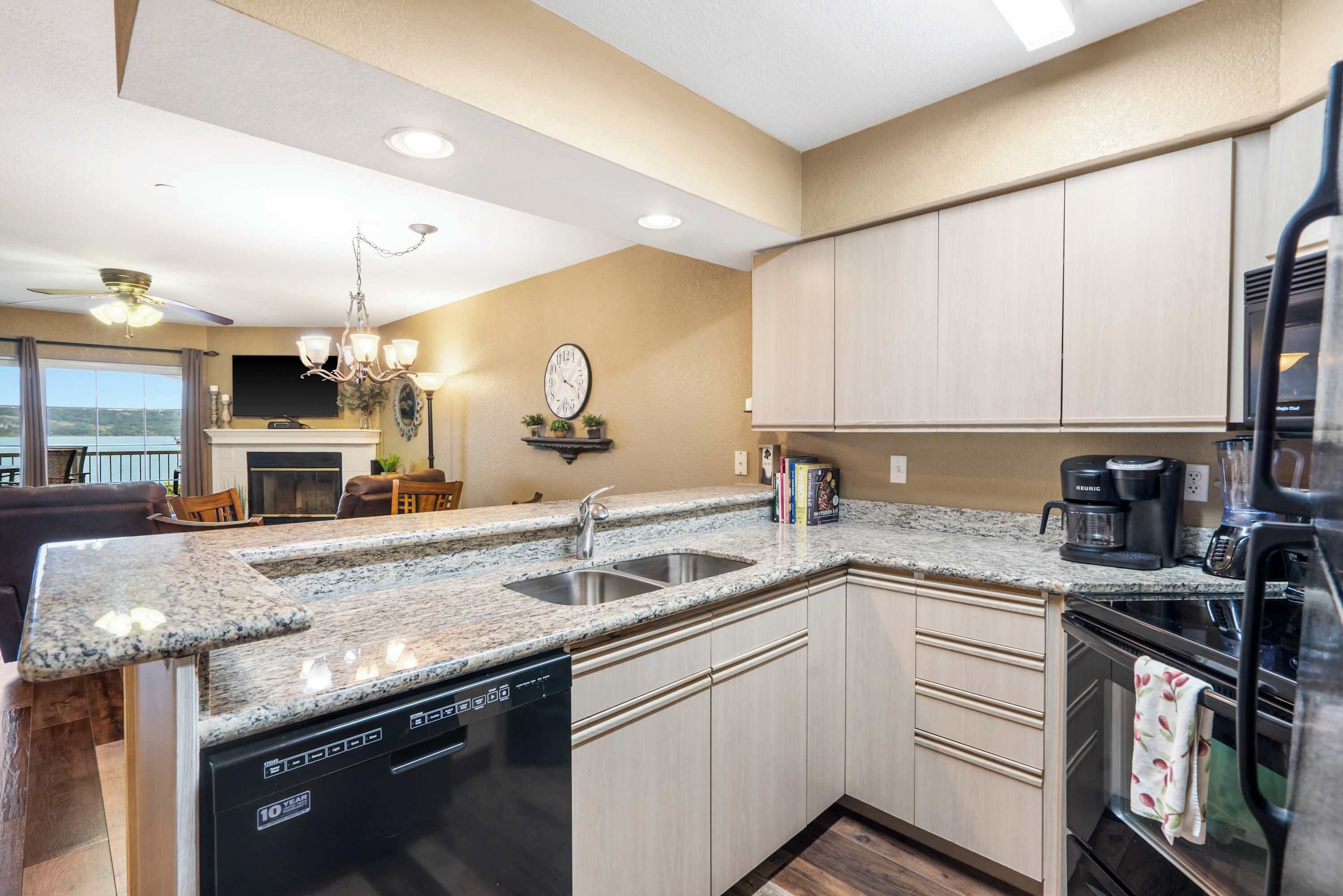 A kitchen with granite countertops, a dishwasher, a coffee maker, and a refrigerator.