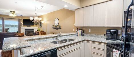A kitchen with granite countertops, a dishwasher, a coffee maker, and a refrigerator.