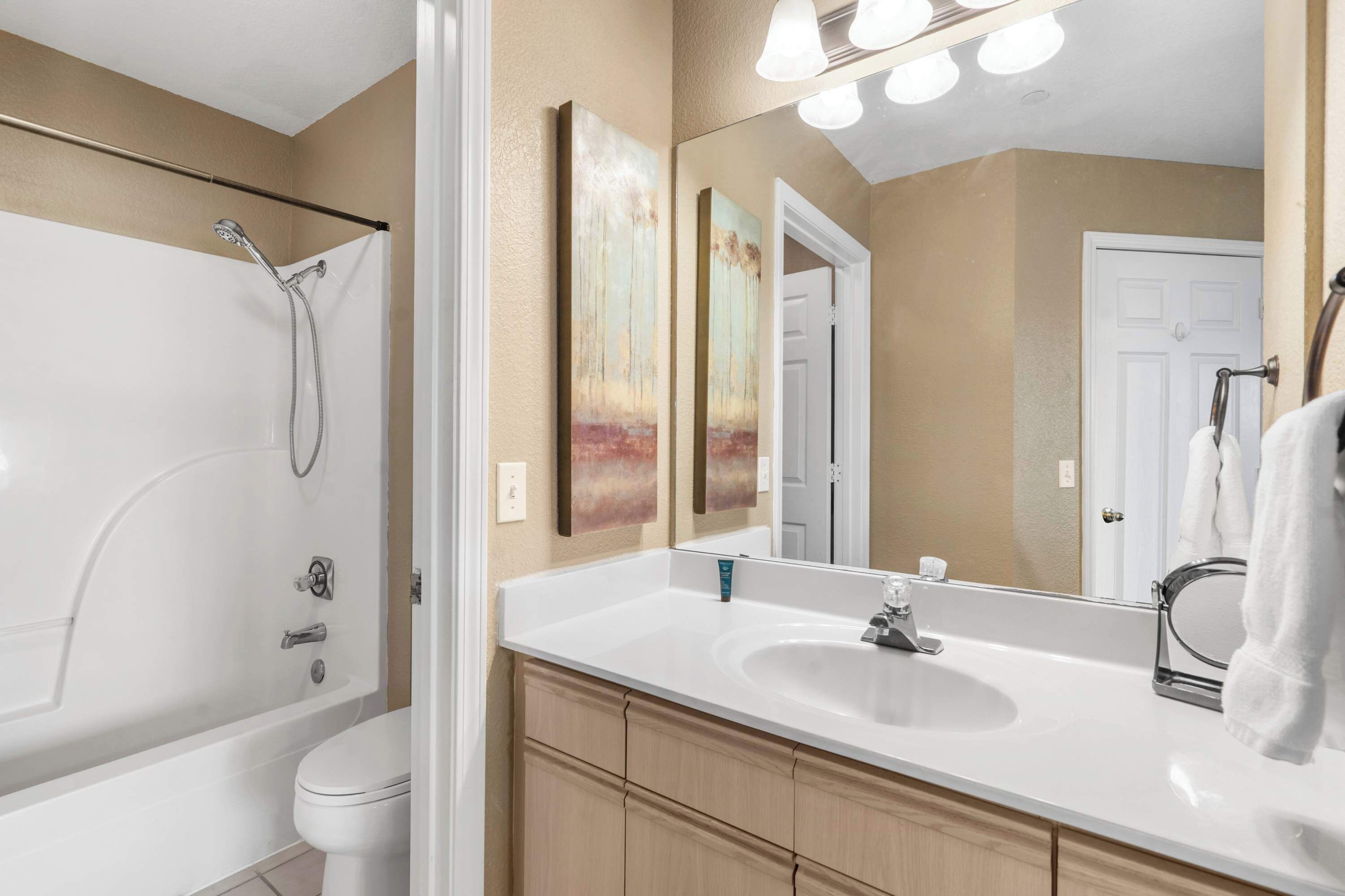 A modern bathroom with a bathtub, toilet, sink, and a large mirror.