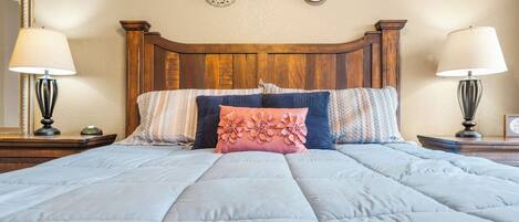 A neatly made bed with a wooden headboard, two bedside lamps, and decorative wall art.