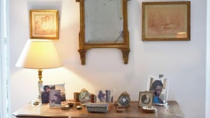 A room with a wooden table, a lamp, and framed pictures on the wall.