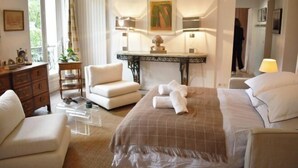 A hotel room with a bed, a desk, a chair, a dresser, and a window.