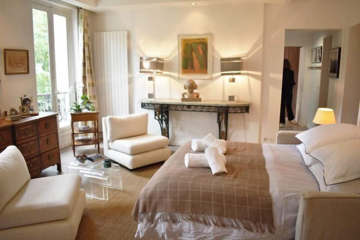 A hotel room with a bed, a desk, a chair, a dresser, and a window.