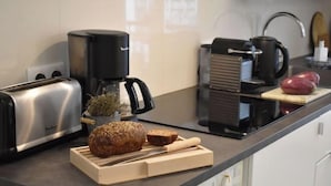 A kitchen with a toaster, coffee maker, and bread on the counter.